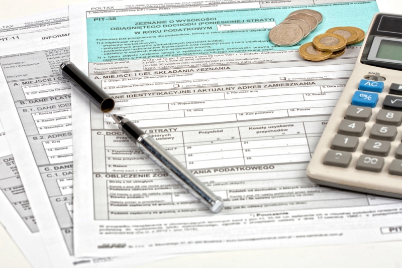 Formularze podatkowe, kalkulator, długopis i monety ułożone na stole, symbolizujące rozliczenie ulgi podatkowej na dzieci